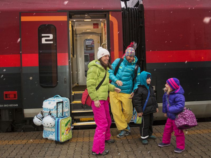 Familie fährt mit Zug nach St. Johann in Tirol
