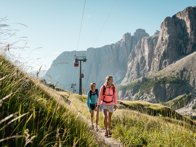 Zwei Mädels wandern vor Bergkulisse in Alta Badia