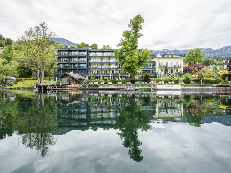 Das Hotel Villa Postillion am See spiegelt sich im klaren Wasser